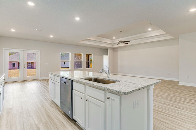 kitchen featuring dishwasher, a center island with sink, a tray ceiling, white cabinetry, and sink