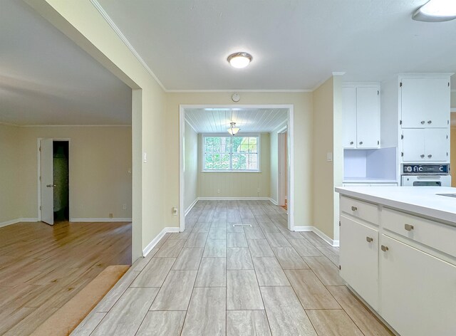 1514 Sharon Rd, Tallahassee, FL 32303 - kitchen featuring light wood finished floors, oven, light countertops, white cabinetry, and crown molding