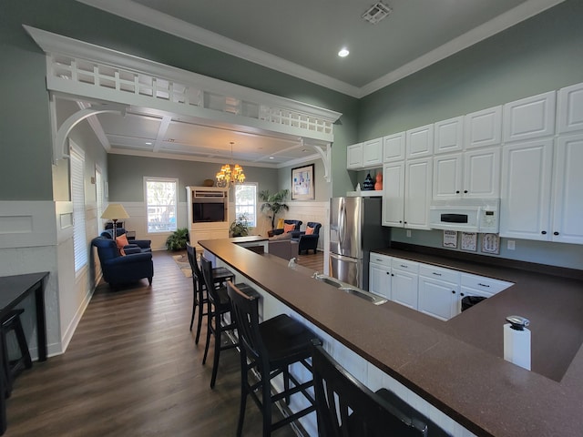 kitchen featuring a kitchen bar, stainless steel fridge, white cabinets, and pendant lighting