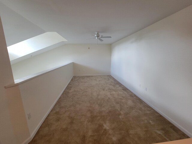 additional living space with a skylight, light carpet, and ceiling fan