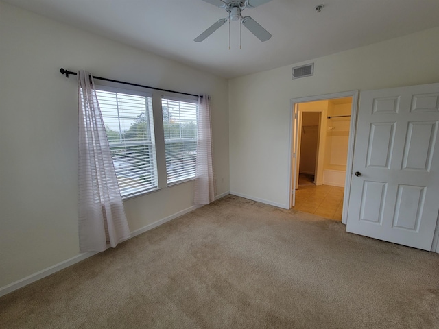 unfurnished bedroom featuring a spacious closet, a closet, ceiling fan, and light colored carpet