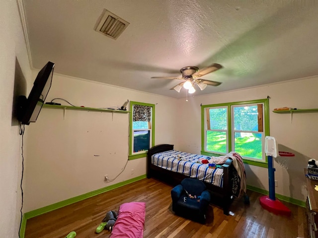 bedroom featuring hardwood / wood-style floors, ceiling fan, a textured ceiling, and crown molding