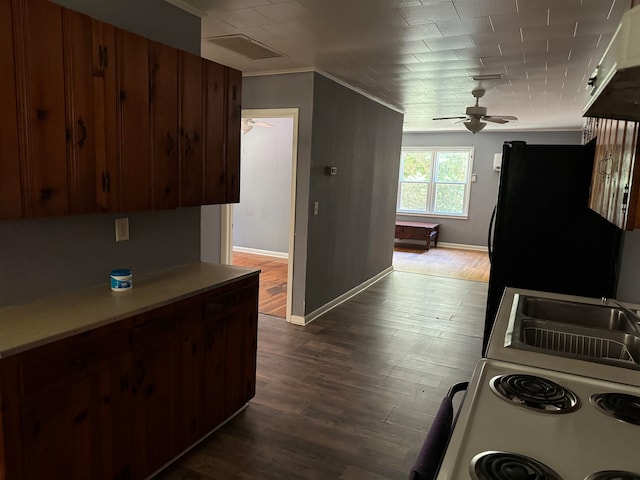 kitchen featuring dark wood-type flooring, ornamental molding, black fridge, and ceiling fan