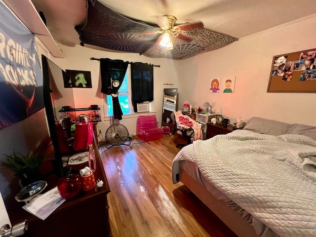 bedroom with cooling unit, hardwood / wood-style floors, and ceiling fan