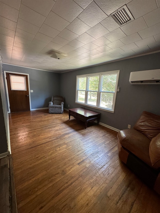 sitting room with wood-type flooring, a wall mounted AC, and crown molding