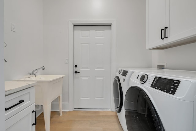 washroom featuring cabinets, washing machine and dryer, and light hardwood / wood-style flooring