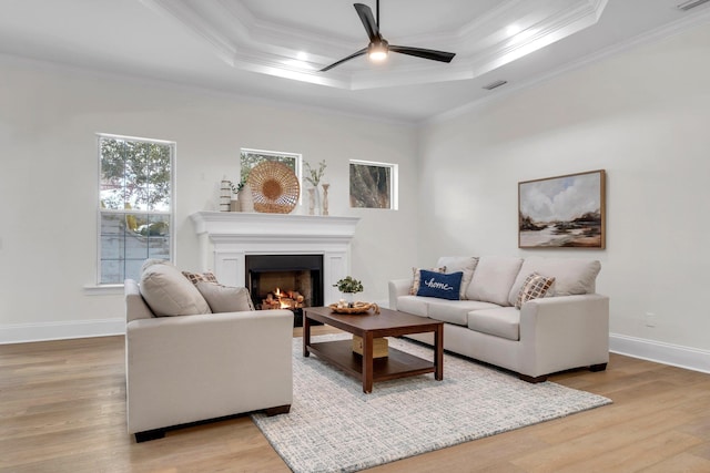 living room with a raised ceiling, ornamental molding, and hardwood / wood-style floors