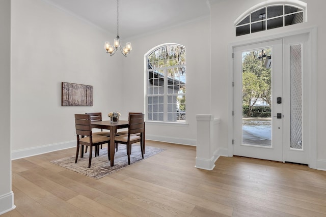 dining area with a notable chandelier, crown molding, and light hardwood / wood-style floors