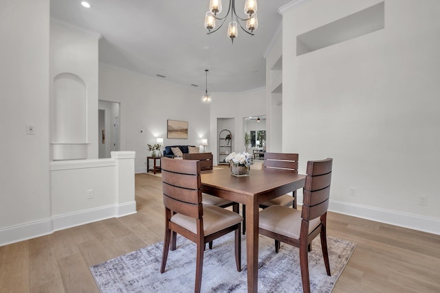 dining space featuring an inviting chandelier, ornamental molding, and light hardwood / wood-style floors