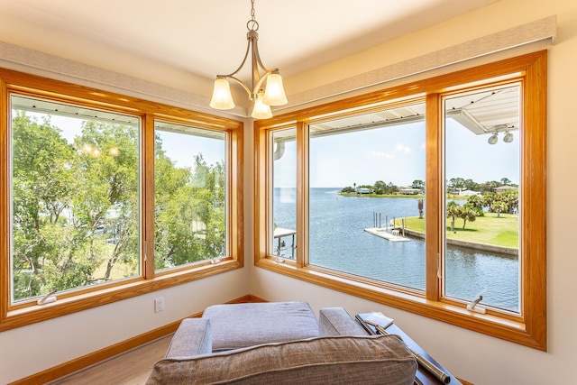 sunroom / solarium with plenty of natural light, a water view, and a notable chandelier