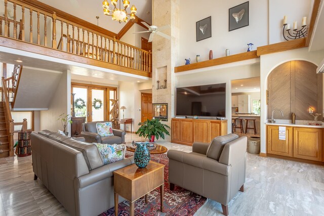 living room with a high ceiling and ceiling fan with notable chandelier