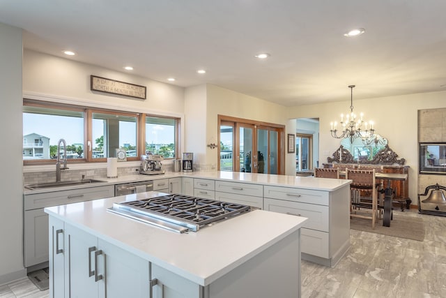 kitchen with hanging light fixtures, sink, appliances with stainless steel finishes, a kitchen island, and kitchen peninsula