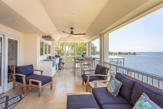 view of patio / terrace with ceiling fan, a water view, and an outdoor living space