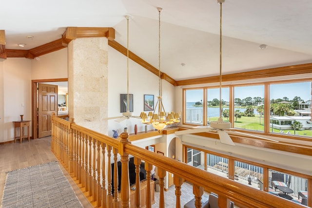 corridor with hardwood / wood-style floors, a water view, high vaulted ceiling, and an inviting chandelier