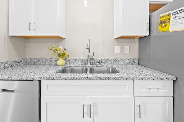 2328 Southampton Dr, Tallahassee, FL 32311 - kitchen with stainless steel dishwasher, a sink, white cabinets, and light stone counters