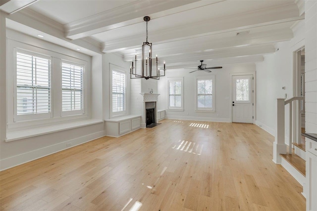 unfurnished living room with light wood finished floors, beamed ceiling, plenty of natural light, and a fireplace with flush hearth