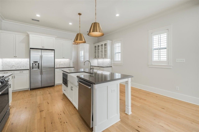 kitchen featuring dark countertops, light wood-type flooring, appliances with stainless steel finishes, and ornamental molding