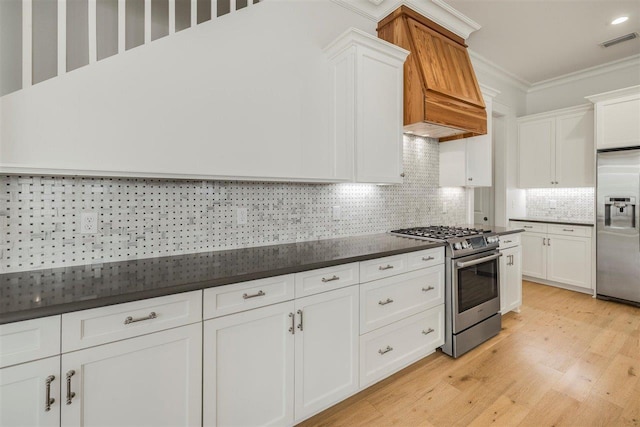 kitchen with white cabinetry, visible vents, appliances with stainless steel finishes, dark countertops, and crown molding