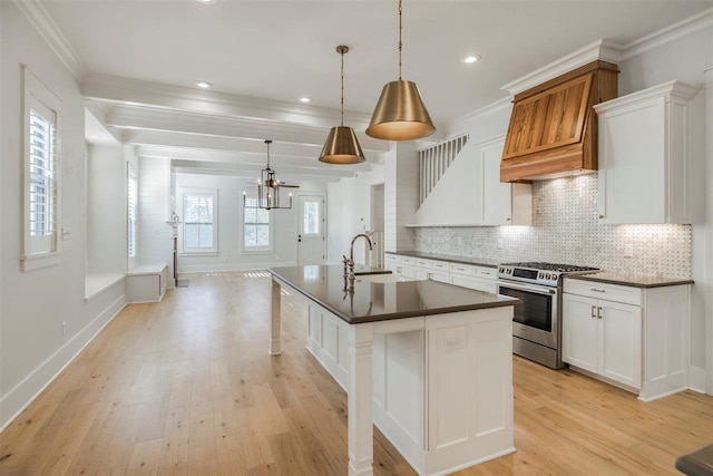 kitchen featuring light wood-style floors, stainless steel gas range, decorative backsplash, dark countertops, and crown molding