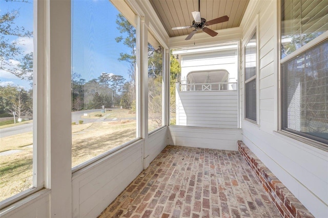 unfurnished sunroom with a healthy amount of sunlight, ceiling fan, and wood ceiling