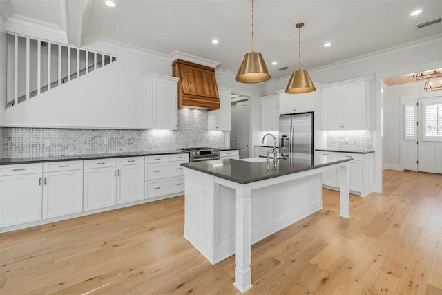 kitchen with crown molding, stainless steel appliances, dark countertops, white cabinets, and a sink