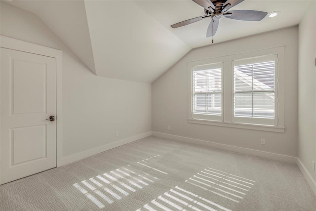 additional living space with vaulted ceiling, ceiling fan, light colored carpet, and baseboards