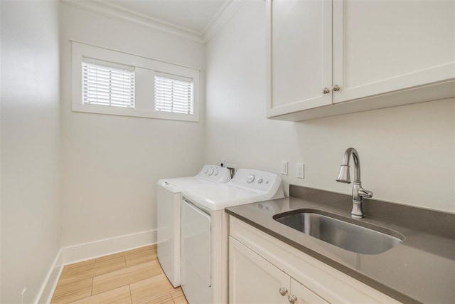 washroom featuring crown molding, cabinet space, a sink, separate washer and dryer, and baseboards