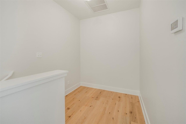 spare room featuring light wood-type flooring, visible vents, and baseboards