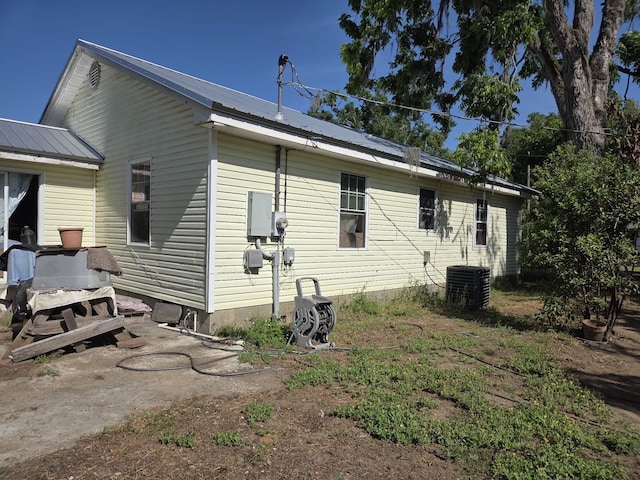 back of property with central AC unit and metal roof