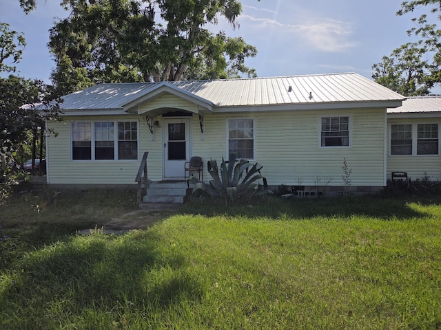 view of front of property featuring metal roof and a front lawn