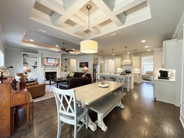 dining room with dark wood-type flooring, ornamental molding, ceiling fan, and a fireplace