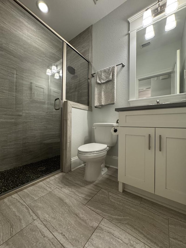 full bath with visible vents, vanity, toilet, baseboards, and a shower stall