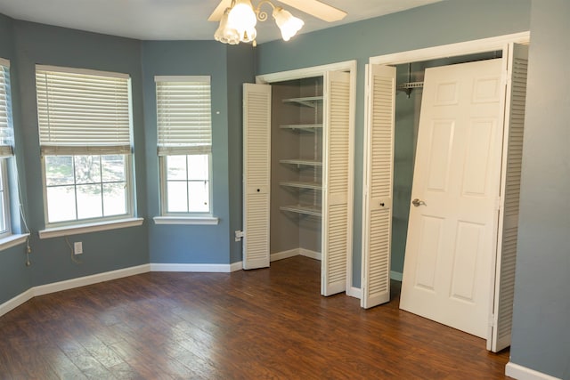 unfurnished bedroom with multiple closets, dark hardwood / wood-style floors, and ceiling fan