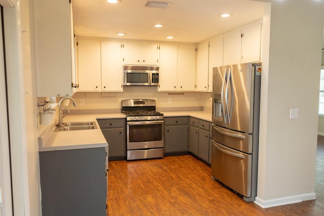 kitchen featuring sink, white cabinetry, dark hardwood / wood-style flooring, gray cabinets, and stainless steel appliances