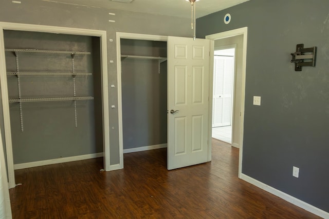 unfurnished bedroom with dark hardwood / wood-style floors and two closets