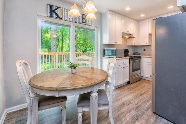 kitchen with a chandelier, appliances with stainless steel finishes, light hardwood / wood-style floors, pendant lighting, and white cabinetry