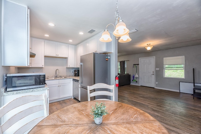 dining space featuring sink, hardwood / wood-style floors, and a notable chandelier