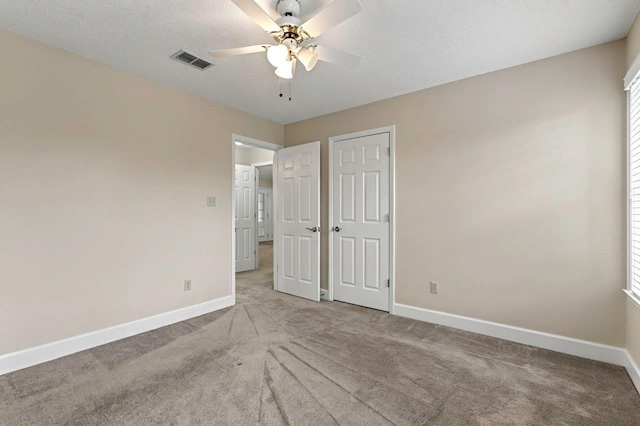 unfurnished bedroom featuring light carpet, ceiling fan, and a textured ceiling