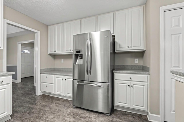 kitchen with a textured ceiling, white cabinets, and stainless steel refrigerator with ice dispenser