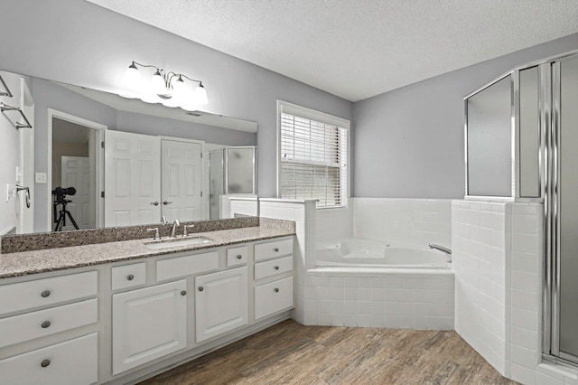 bathroom with vanity, separate shower and tub, wood-type flooring, and a textured ceiling