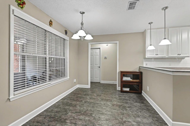 unfurnished dining area with a textured ceiling and a notable chandelier