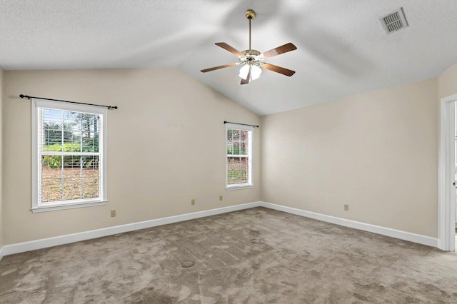 spare room with ceiling fan, lofted ceiling, light colored carpet, and a textured ceiling