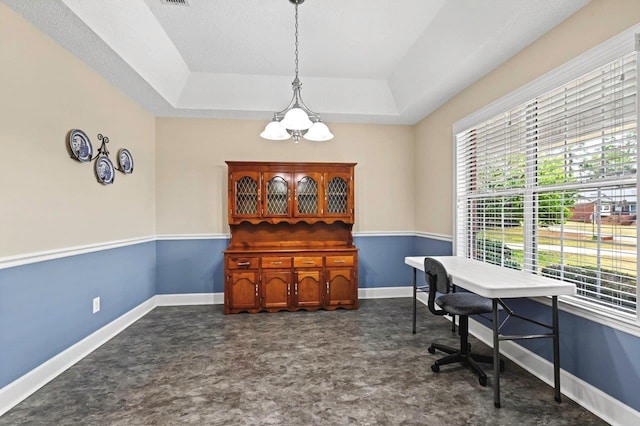 office with a raised ceiling and a notable chandelier