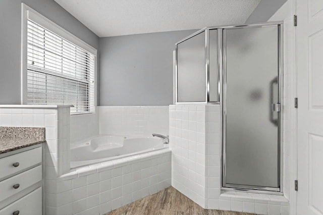 bathroom featuring vanity, wood-type flooring, a textured ceiling, and separate shower and tub