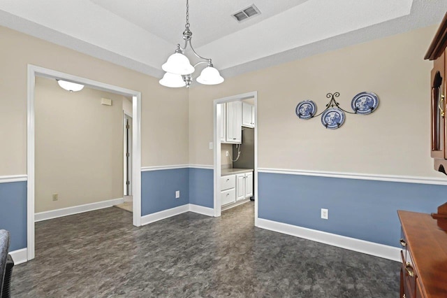 unfurnished dining area with an inviting chandelier and a raised ceiling