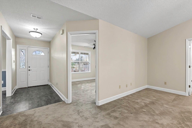 carpeted foyer entrance with a textured ceiling