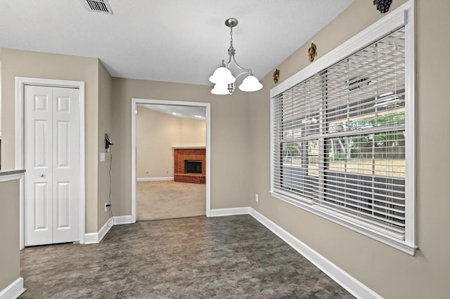 unfurnished dining area with a textured ceiling, a fireplace, and a chandelier