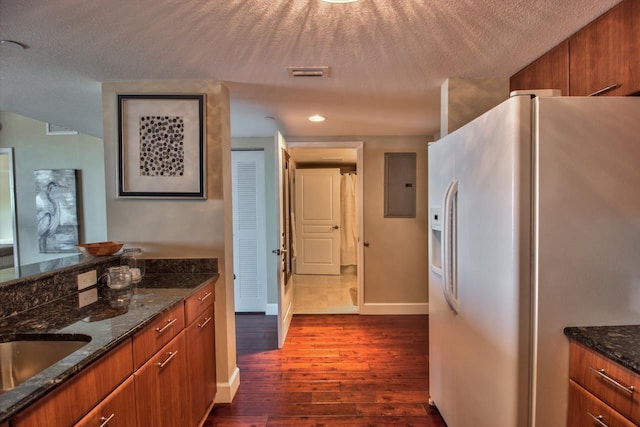 300 S Duval St Unit 1411, Tallahassee, FL 32301 - kitchen with white fridge with ice dispenser, electric panel, dark wood-type flooring, brown cabinetry, and dark stone countertops