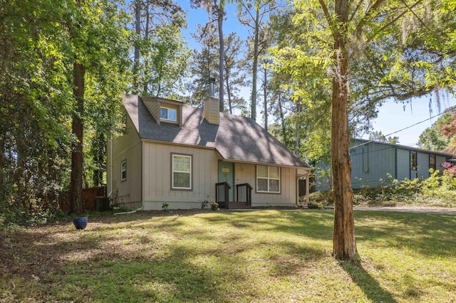view of front of home with a front yard, roof with shingles, a chimney, and central AC unit