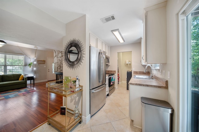 kitchen with stainless steel appliances, a sink, open floor plan, plenty of natural light, and visible vents